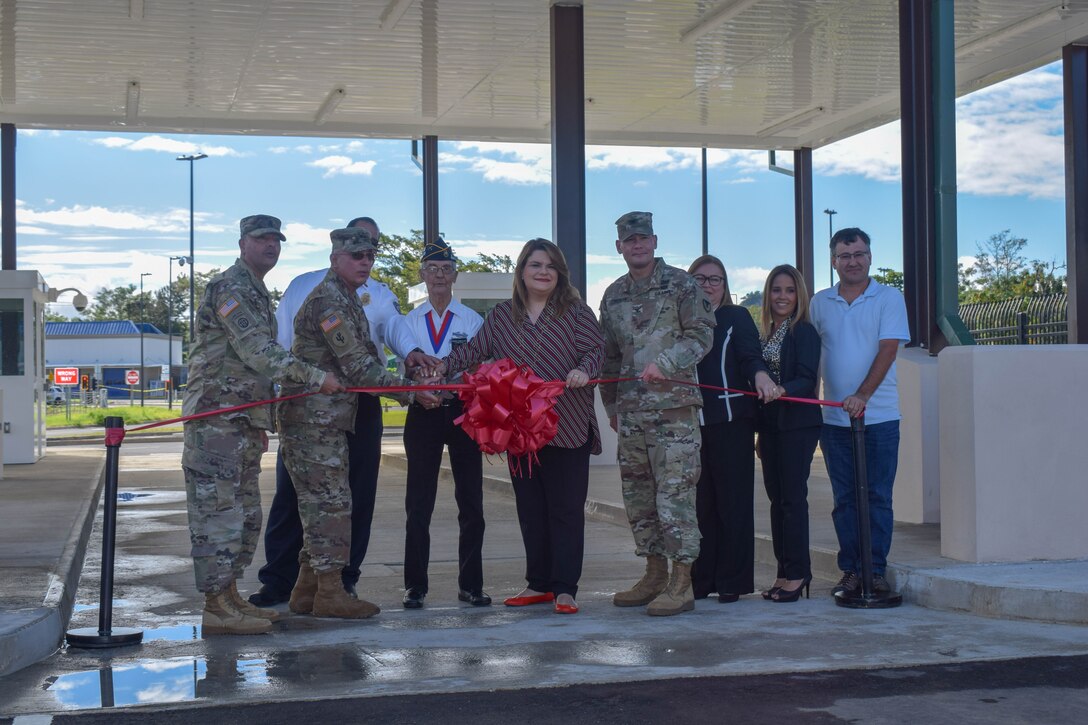 Nine people standing behind a red ribbon