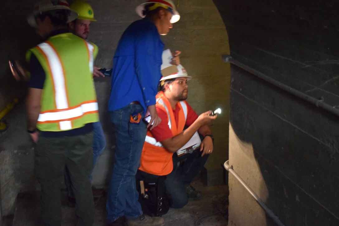 Four men wearing personal protective equipment during a dam inspection