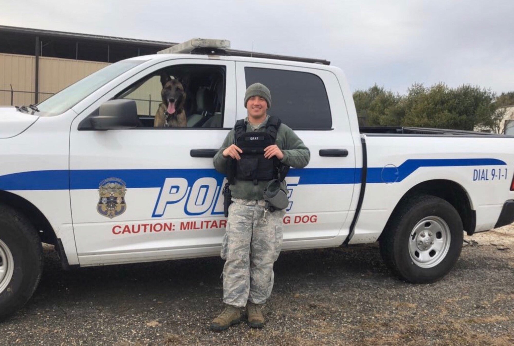 An Airman and a military working dog pose for a photo.