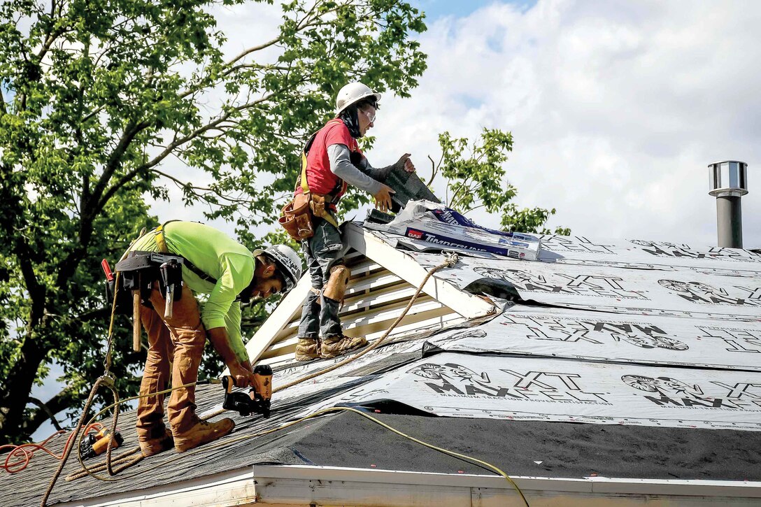 Roofers lay shingles on a home.