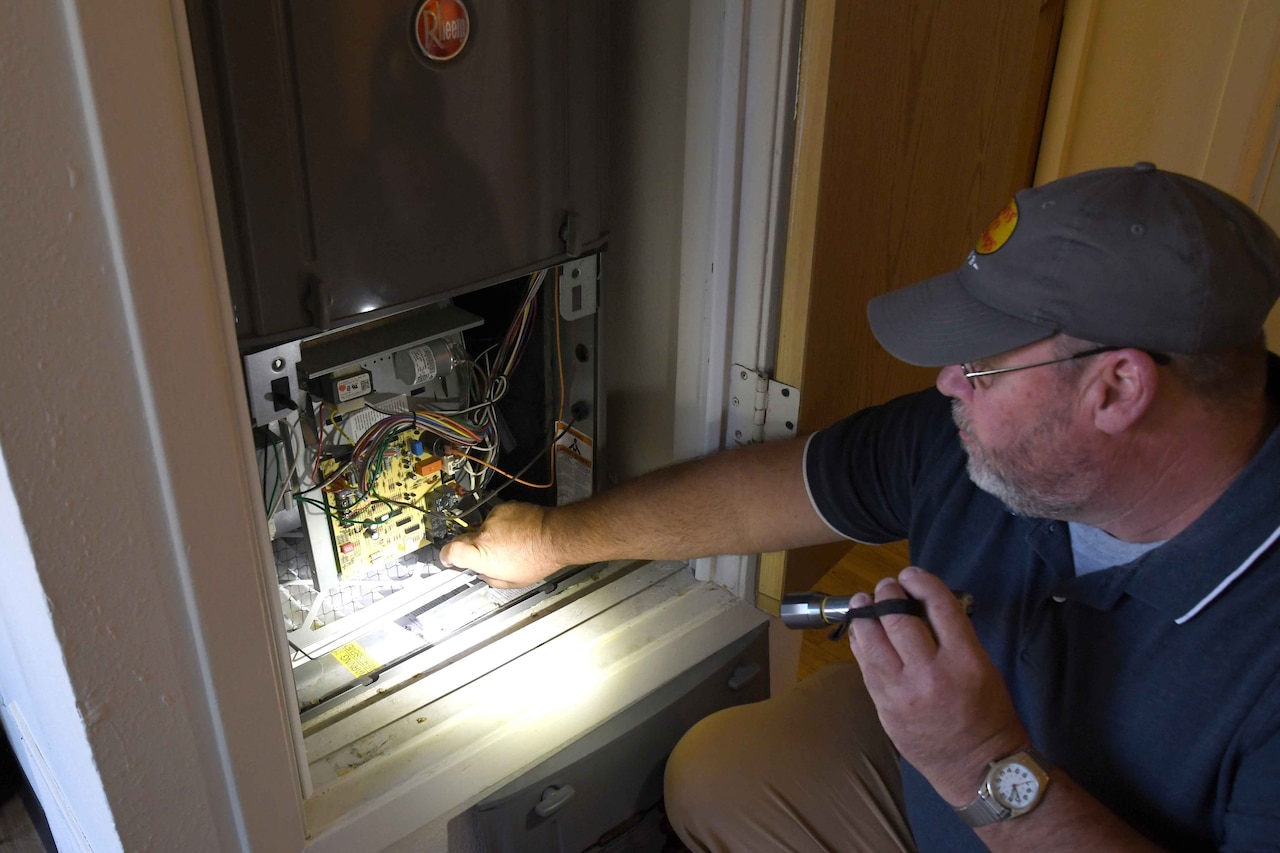 A man inspects an HVAC unit.