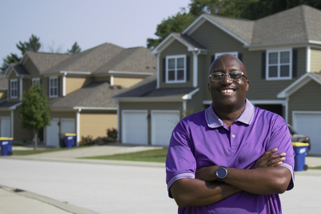 A man stands with folded arms in a housing community.