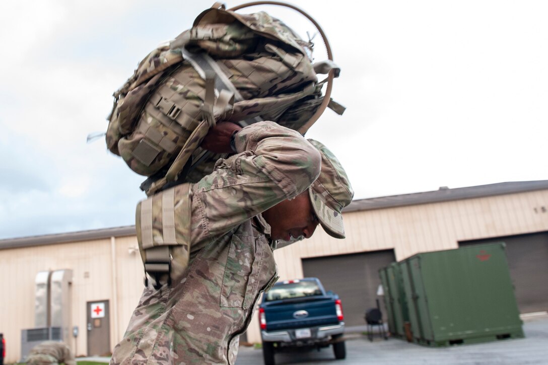 A photo of an Airman picking up a ruck sack.