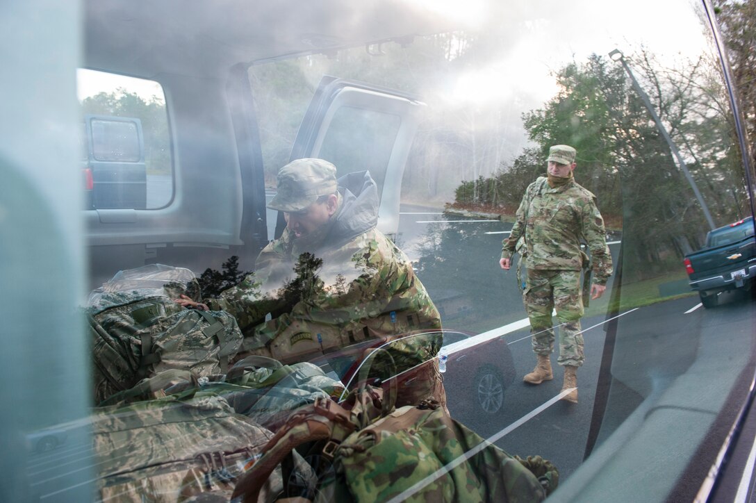 A photo of an Airman putting a ruck sack into a van.