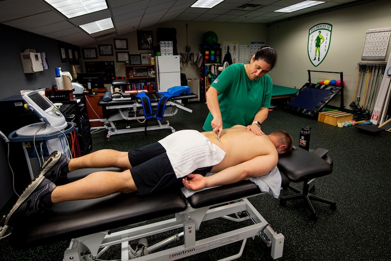 Photo of an athletic trainer performing muscle scraping on a patient.