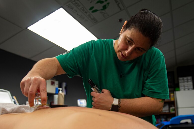 Photo of athletic trainer beginning air cupping therapy on a patient.