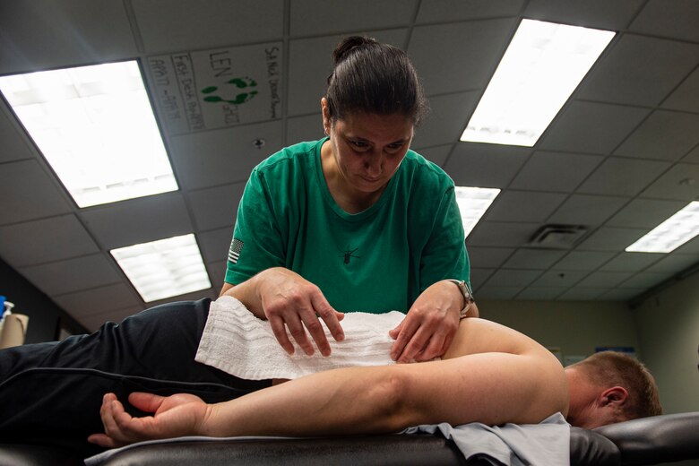 Photo of an athletic trainer leans on a patient’s back.