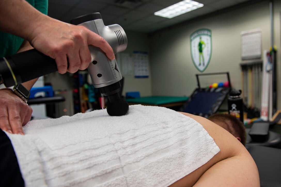 Photo of an athletic trainer performing muscle sculpting on a patient.