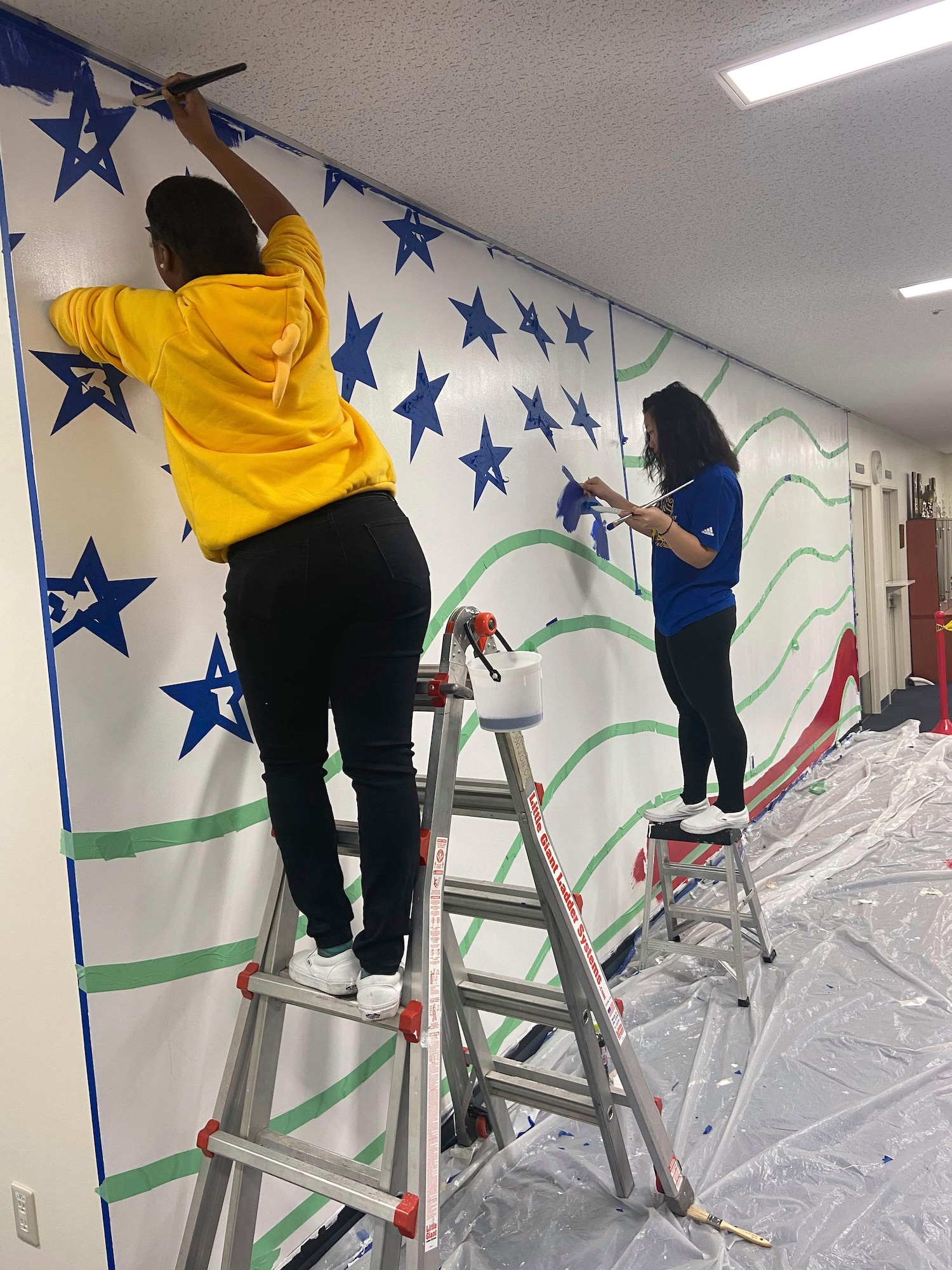 (Left to right) Airman 1st Class Te’Anne Dailey, and Airman 1st Class Deborah Kang, both 374th Security Forces Squadron patrolman, paint a mural at a main lobby of SFS’s building at Yokota Air Base, Japan, Feb. 2, 2020.