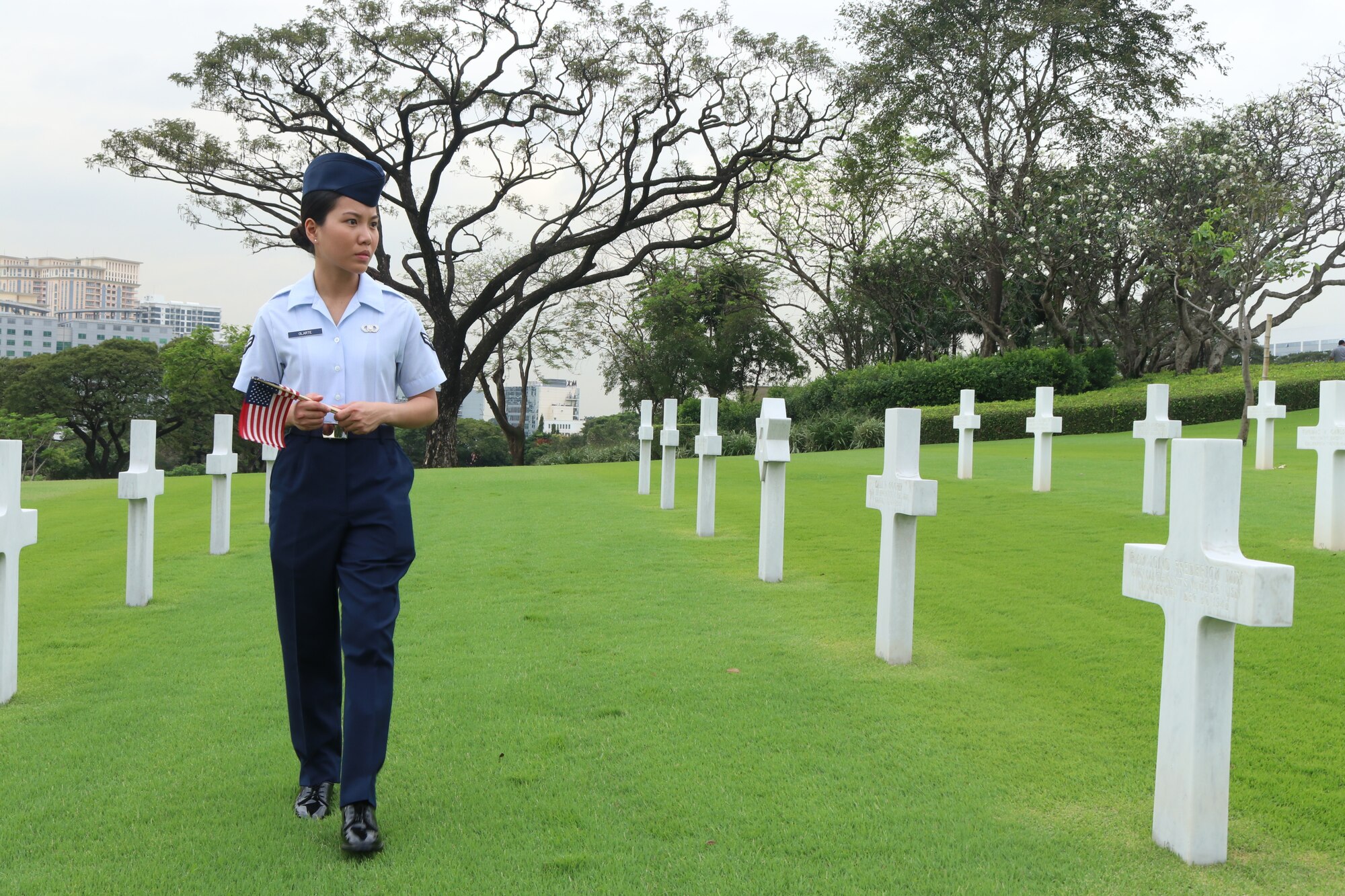 Airman 1st Class Ana Olarke, 317th Operations Support Squadron aircrew flight equipment journeyman, carries an American flag to place by a gravestone of a fallen service member of the 317th Airlift Wing at the Manila American Cemetery in Manila, Philippines, Feb. 17, 2020.