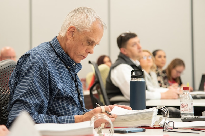 Ralph Campbell, U.S. Army Engineering and Support Center, Huntsville Ordnance and Explosives director, studies slides during the monthly Project Review Board Feb. 12 in Huntsville, Alabama. (Photo by Stephen Baack, Huntsville Center public affairs.)