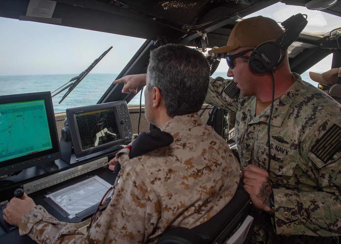 JUBAIL, Kingdom of Saudi Arabia 200223-N-JO908-1073
Gunner’s Mate 1st Class Andrew Davies, assigned to Commander Task Force 56, guides Rear Adm. Majed Haz'z Al-Kahtani, Deputy Commander, Royal Saudi Naval Forces (RSNF) Eastern Fleet, on how to operate a Mark VI patrol boat during an underway as part of exercise Nautical Defender 20 in Jubail, Kingdom of Saudi Arabia Feb. 23. ND is a bilateral maritime exercise between the U.S. Navy and the RSNF designed to build and sustain warfighting capabilities, support long term regional security and enhance military-to-military interoperability with the U.S. and Kingdom of Saudi Arabia. (U.S. Navy photo by Mass Communication Specialist 1st Class Kory Alsberry)