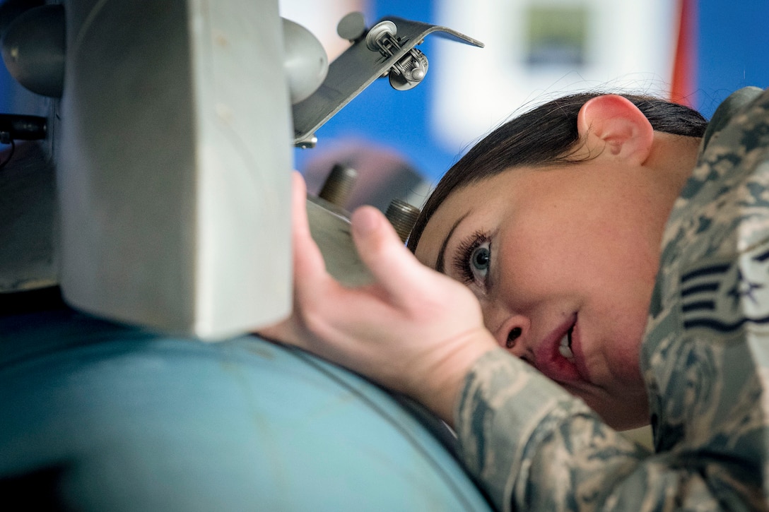 An airman bends over to ensure a Guided Bomb Unit-10 is properly secured.