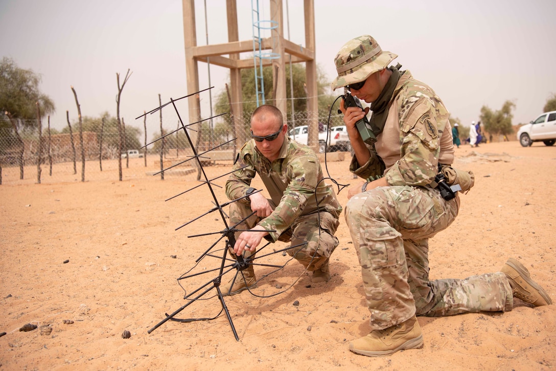 Two soldiers operate an antenna.