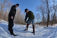 Two men take a snow sample with a snow tube