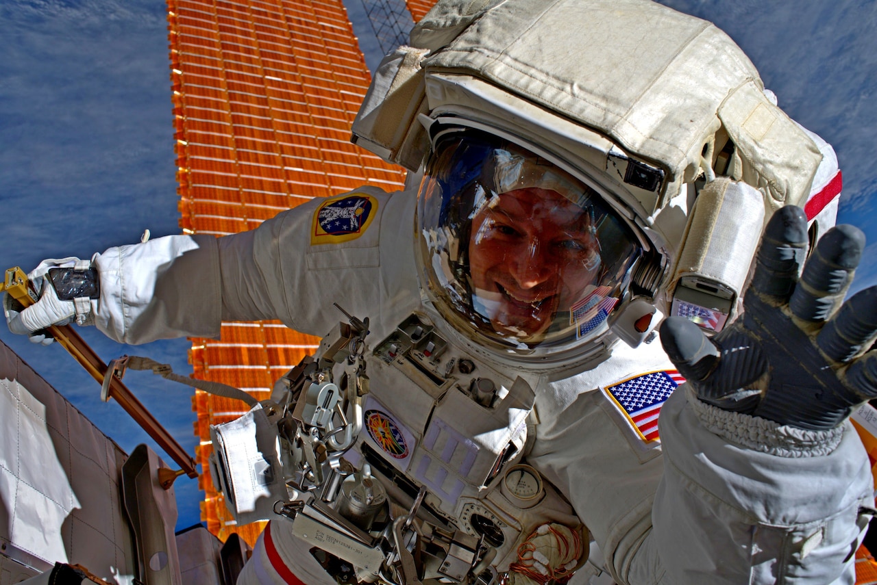 Spacewalking astronaut waves to photographer.
