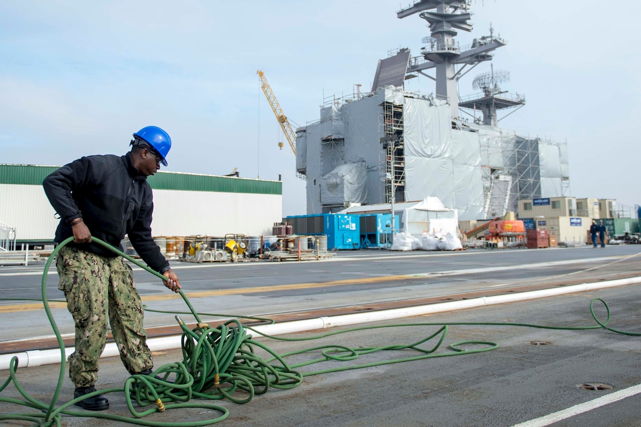 A sailor untangles an air hose.