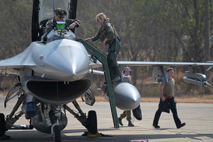 Airmen work on a jet as it sits on a runway.