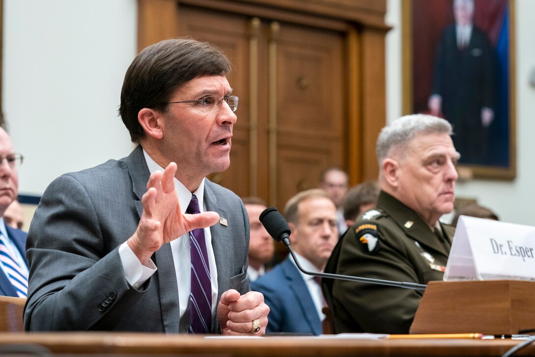 Defense Secretary Dr. Mark T. Esper talks while sitting at a table next to Army Gen. Mark A. Milley.