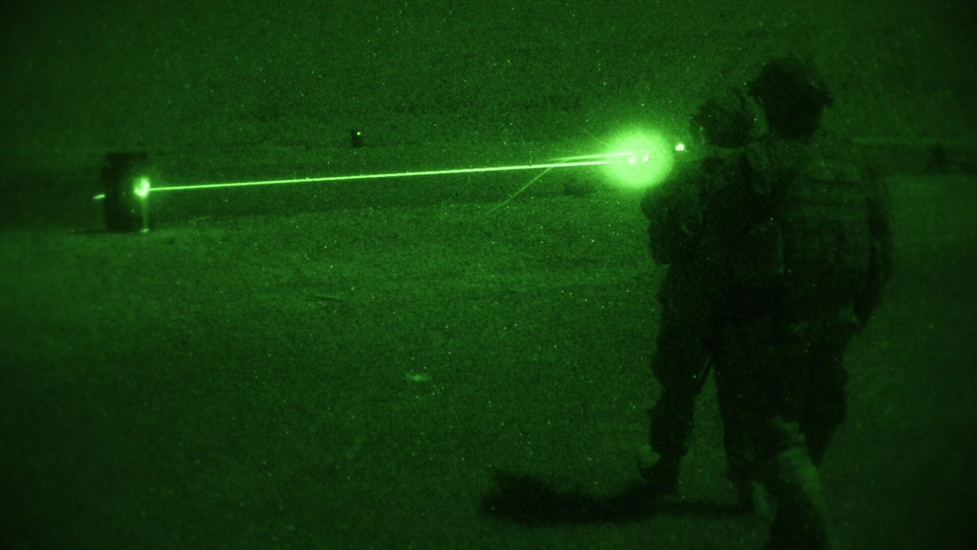 Soldier fires machine gun at night.