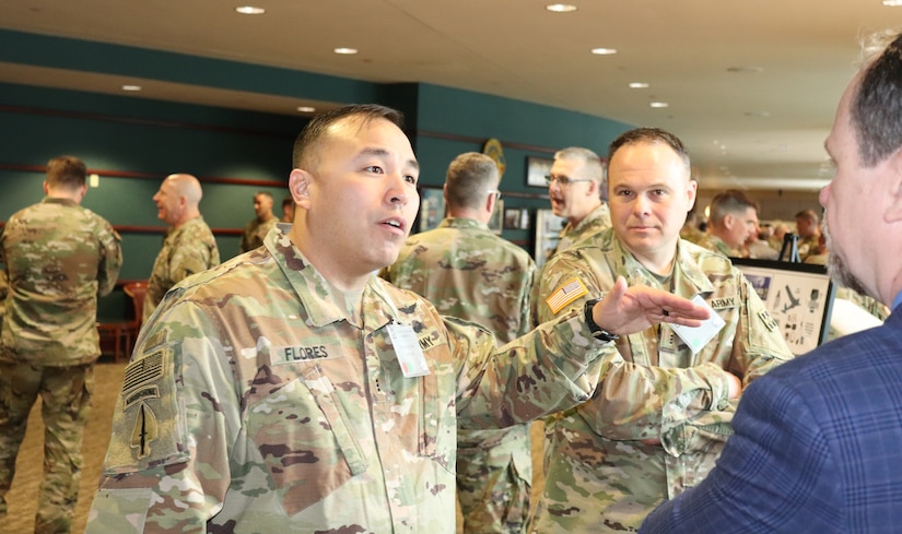 Chief Warrant Officer 3 Jason Flores (left), an Unmanned Aerial Systems (UAS) warrant officer with the 2nd Infantry Division, Fort Carson, Colorado,  discusses UAS operations during a break at the AMCOM 101 for Aviation forum, Feb. 19-20. Several aviation support activates manned information booths in the break area for Soldiers to interact and get answers to specific questions.