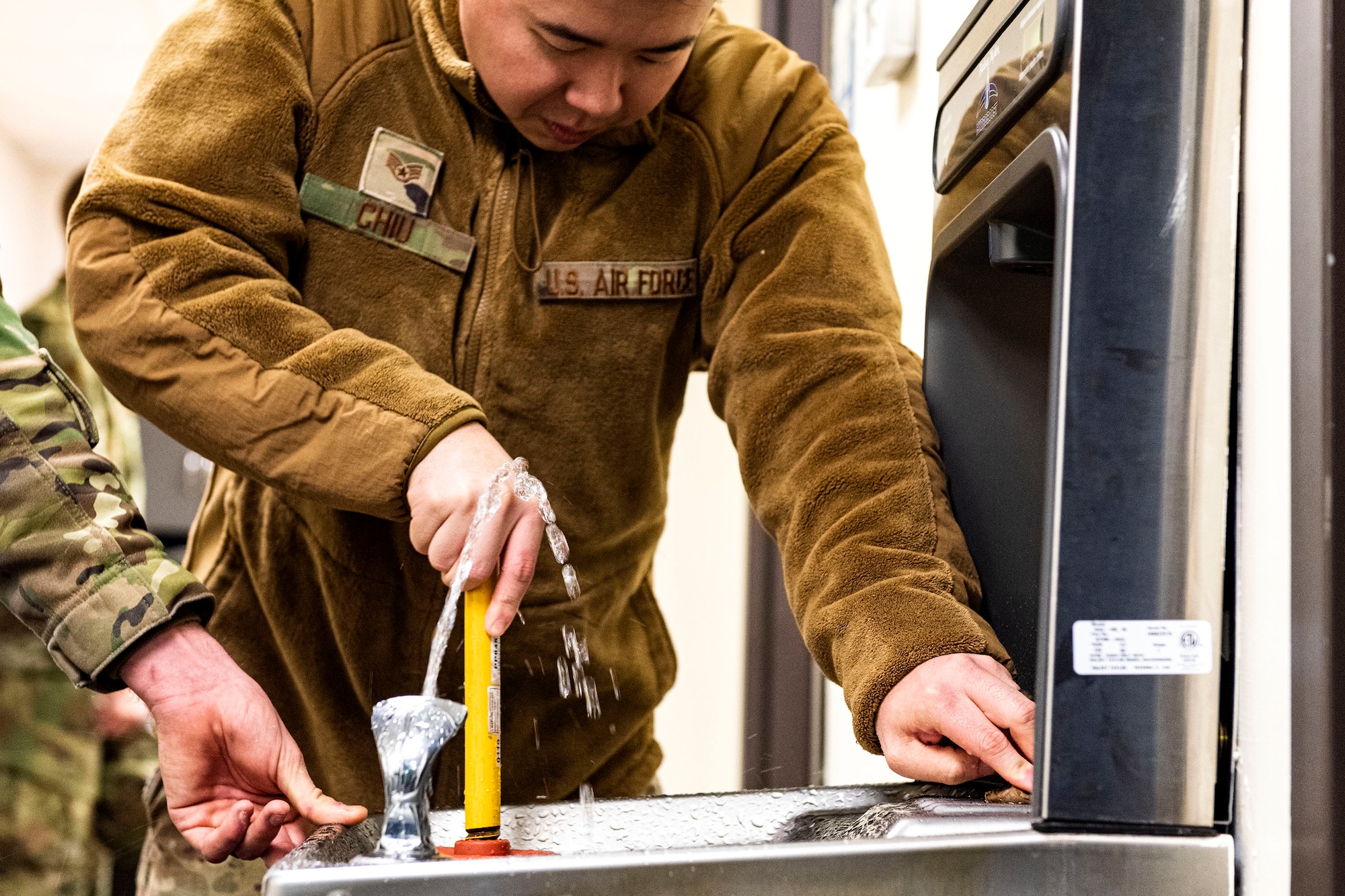 Photo of Airman unclogging a drinking fountain.
