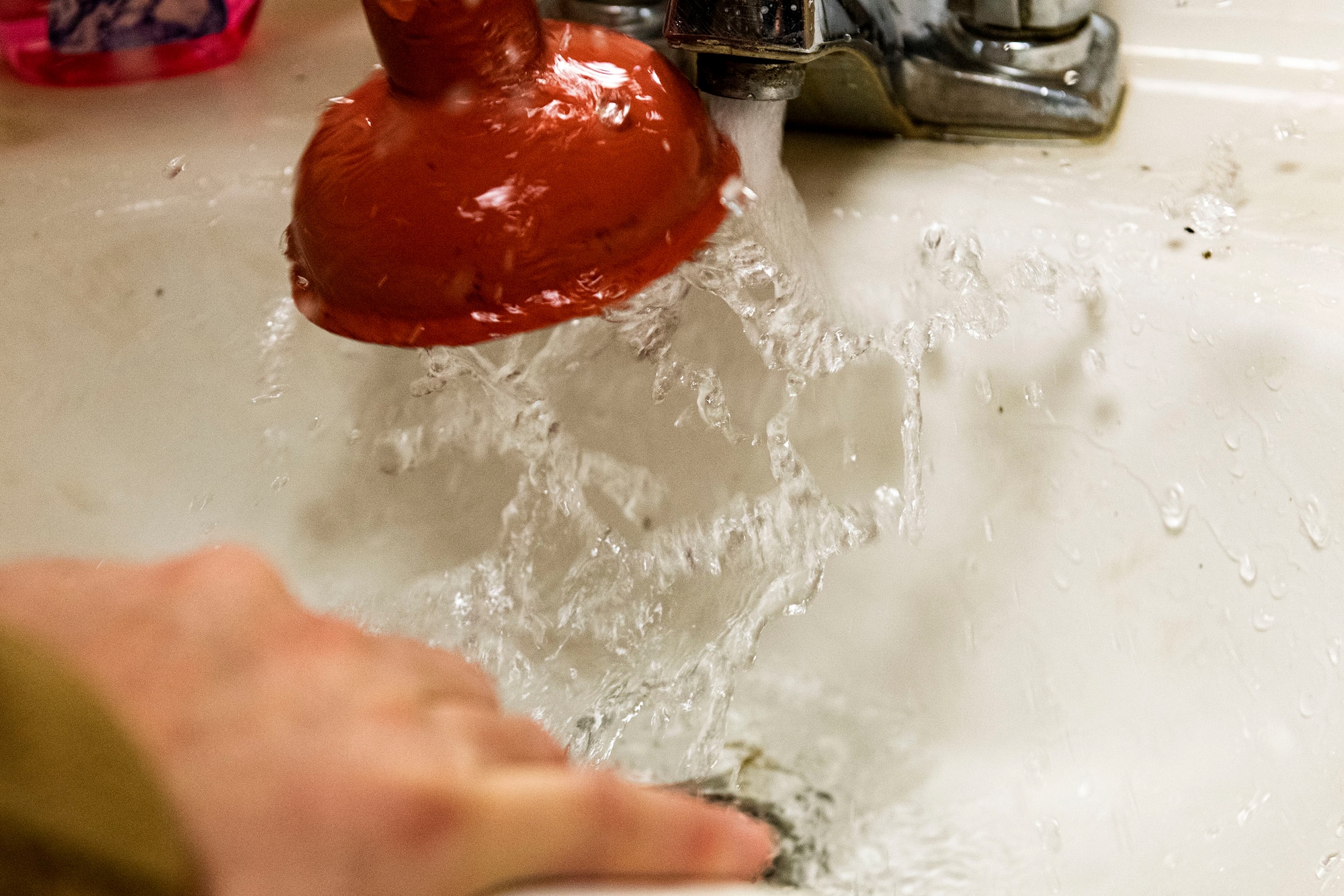 Photo of Airman unclogging a sink.