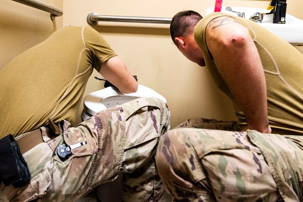 Photo of Airmen fixing a toilet.