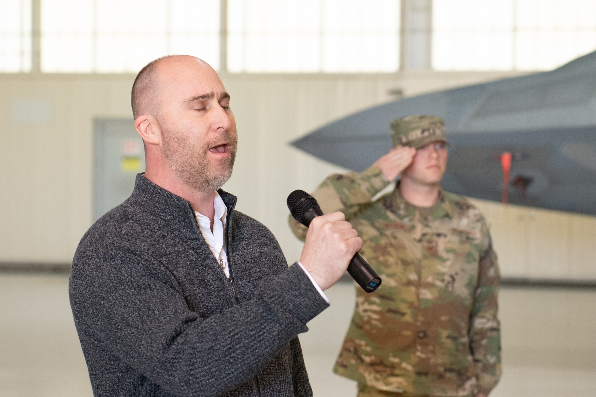 A man sings and an Airman salutes