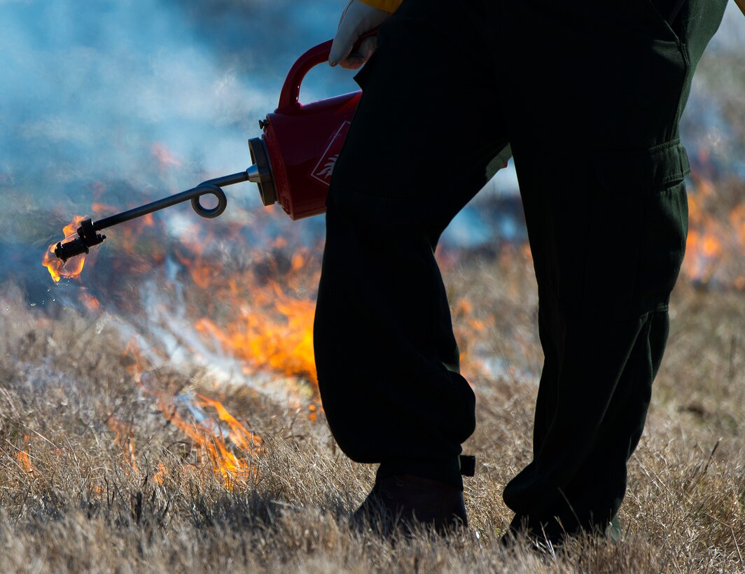 A Wright-Patterson Air Force Base, Ohio, firefighter holds a drip torch after setting a line of fire in a field near the base during a prescribed burn Feb. 21, 2020. The drip torch is designed to safely dispense burning fuel to start fires in the desired spots. (U.S. Air Force photo/R.J. Oriez)