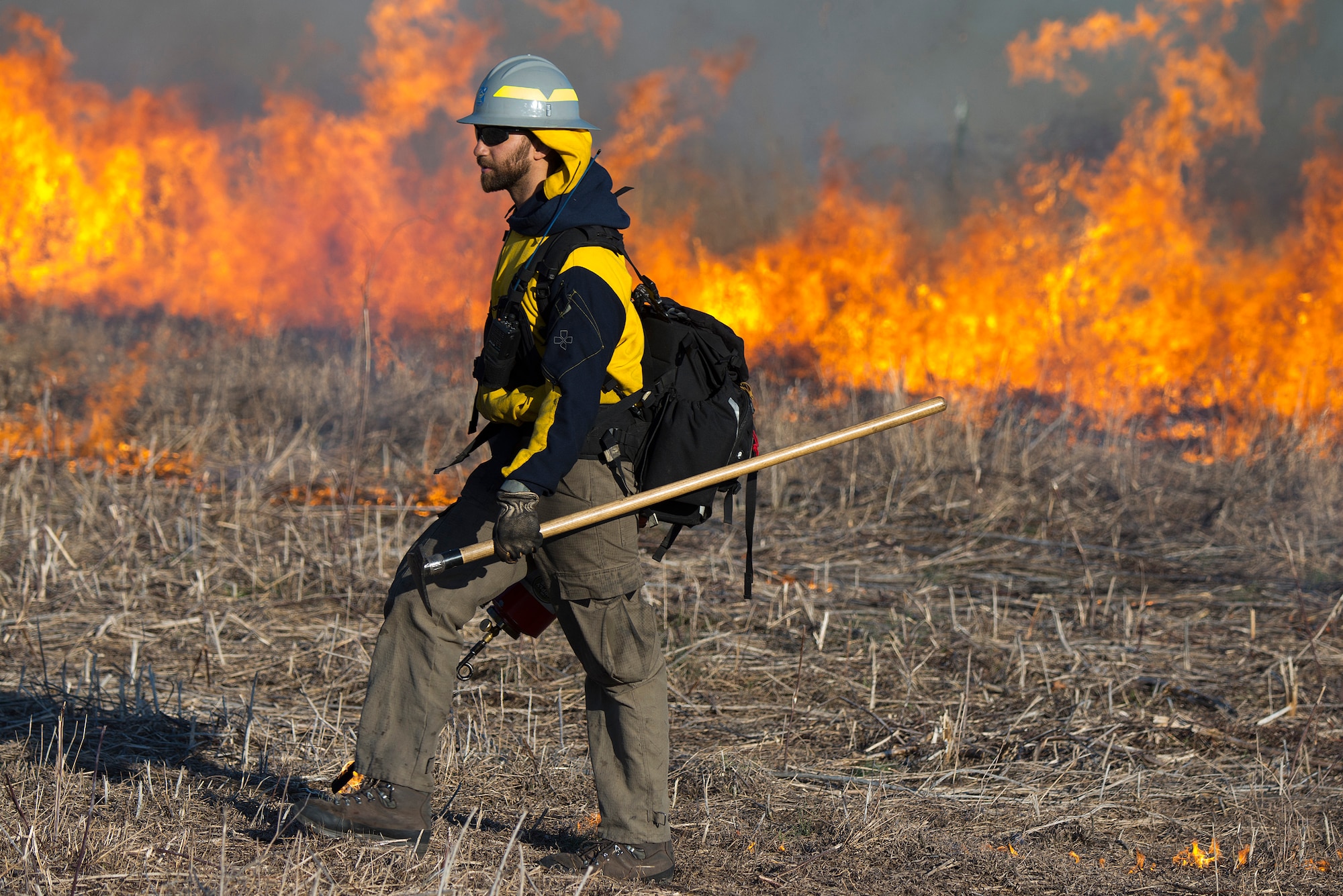 Nick Steel, Air Force Wildland Fire Branch Wildland Support Module, walks with a drip torch Feb. 21, 2020, helping to spread a prescribed burn on Huffman Prairie. Steel’s module came to Wright-Patterson Air Force Base, Ohio, from Joint Base McGuire-Dix-Lakehurst, N.J., to help with the burn. (U.S. Air Force photo/R.J. Oriez)