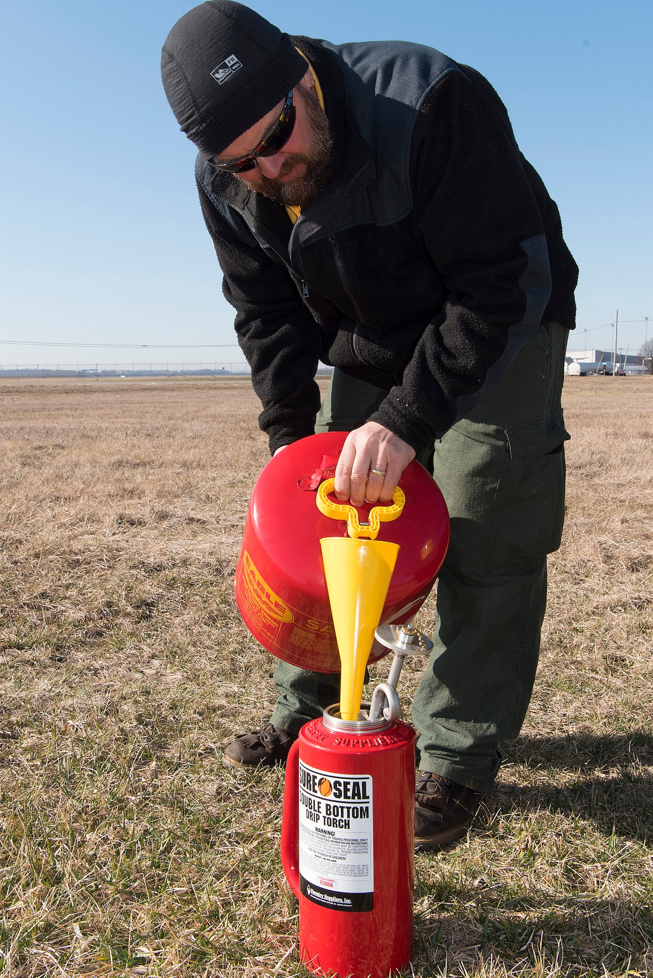 Darryn Warner, 88th Civil Engineering Group Natural Resource Program manager, fills a drip-torch Feb. 21, 2020, in a field near Wright-Patterson Air Force Base, Ohio. Warner was coordinating and overseeing prescribed burns used to help native prairie grass grow. (U.S. Air Force photo/R.J. Oriez)