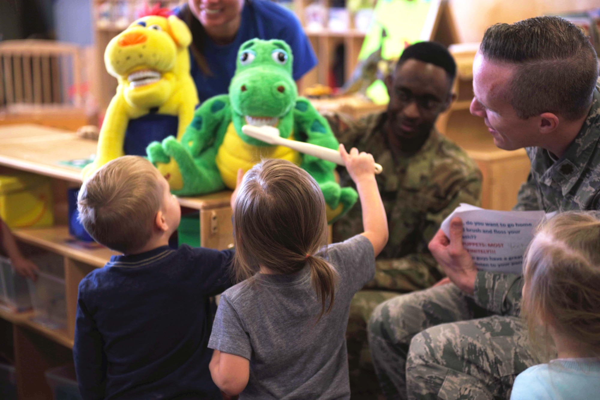 U.S. Air Force Staff Sgt. Myron Little, 325th Medical Group noncommissioned office in charge of dental logistics (right), and U.S. Air Force Maj. Nicholas Einbender, 325th MDG dentist, watch as children pretend to brush the teeth of a puppet during a dental demonstration at Tyndall Air Force Base, Florida, Feb. 27, 2020. February is National Children's Dental Health Month, and the 325th MDG's dental team reached out to the 325th Force Support Squadron's Child and Youth Program Center (formerly known as the Child Development Center) to teach young children the importance of brushing and flossing teeth. (U.S. Air Force photo by Staff Sgt. Magen M. Reeves)