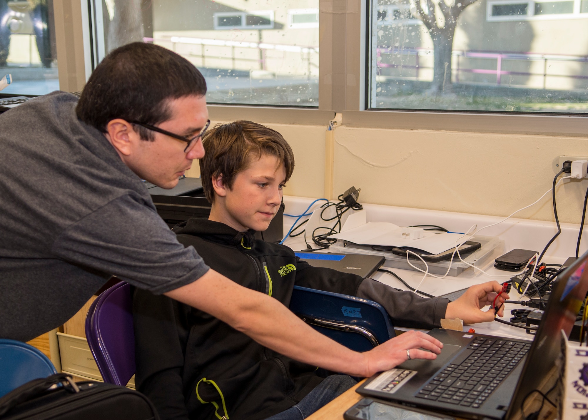 Coach Charles Eger, 773rd Test Squadron, helps Scorpion Robotics Club member Brayden Maye with computer software coding at Desert Junior-Senior High School on Edwards Air Force Base, California, Feb. 12. (Air Force photo by Giancarlo Casem)