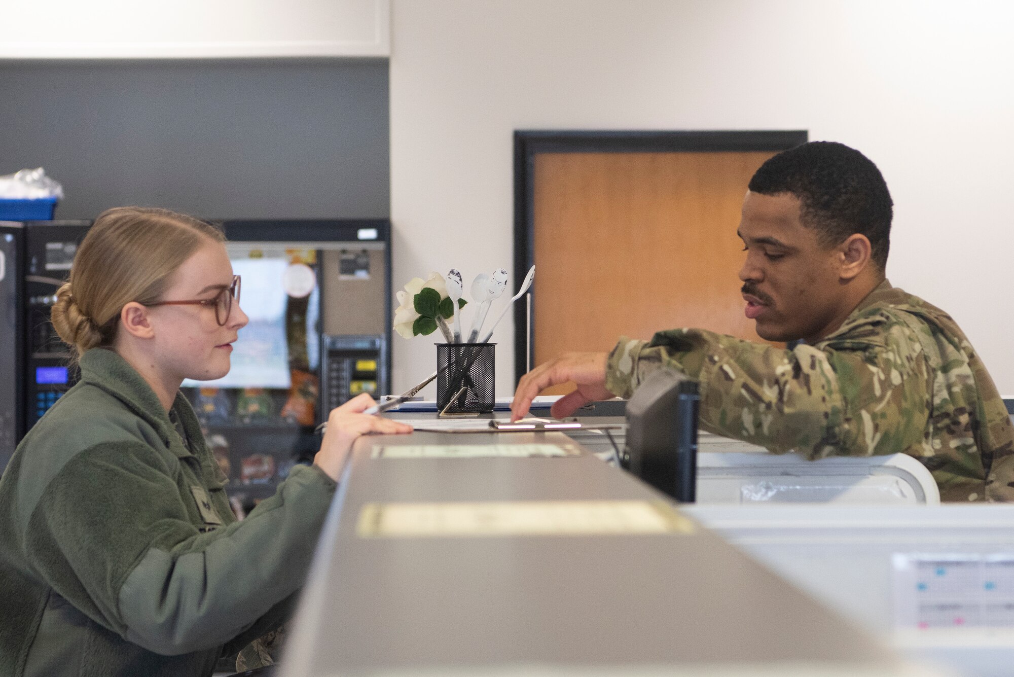 Staff Sgt. Jordan Row, 100th Logistics Readiness Squadron passenger travel and personal property supervisor, discusses travel paperwork with Senior Airman Samantha Roppo, 100th Civil Engineer Squadron commander support staff technician, Feb. 25, 2020, at RAF Mildenhall, England. The passenger travel section of the traffic management office helps organize transportation for deploying Airmen and any weapons they may carry. (U.S. Air Force photo by Airman 1st Class Joseph Barron)