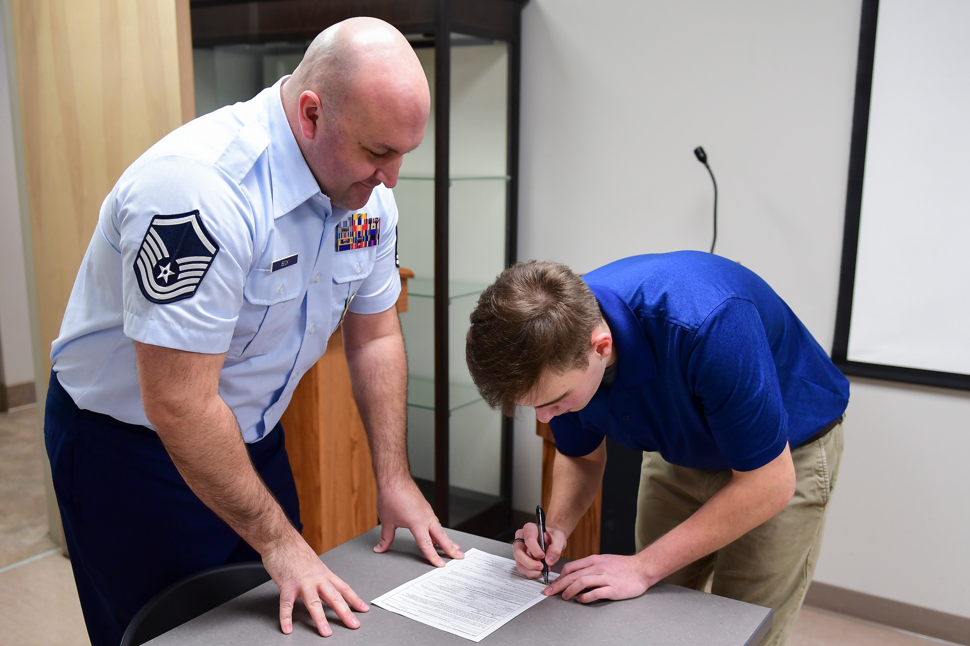 Raymond Gonzalez signs his enlistment paperwork after taking the Oath of Enlistment with Master Sgt. Christopher Beck, recruiter with the 911th Airlift Wing at the Pittsburgh International Airport Air Reserve Station, Pennsylvania, Jan. 31, 2020.