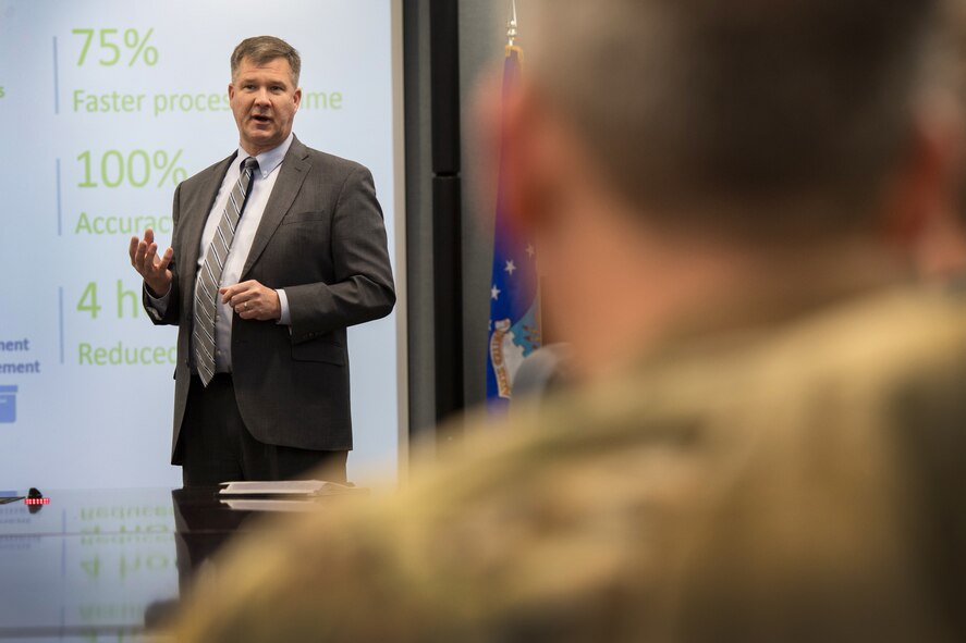 William Ross, Communications and Information Division (SC) director, briefs Col. Chad Ellsworth, 66th Air Base Group commander, on the potential use of robotic process automation during an RPA demonstration at Hanscom Air Force Base, Mass., Feb. 21. By collaborating with UiPath, a global software company that develops a platform for robotic process automation, the division will be able to increase productivity, accuracy, and overall mission success through the help of bots. (U.S. Air Force photo by Jerry Saslav)