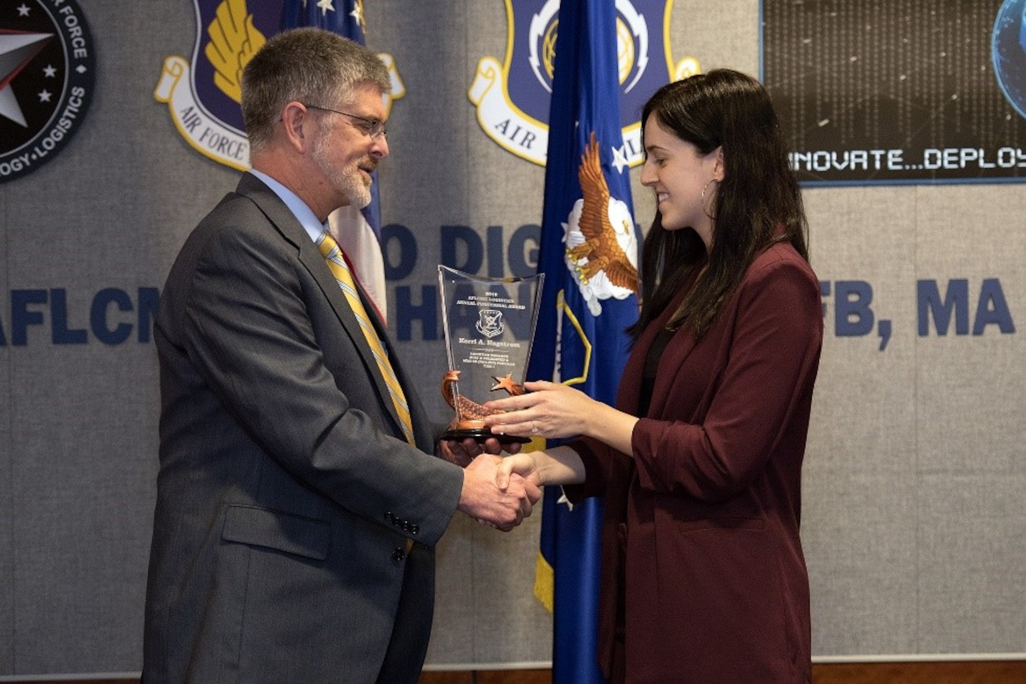 Scott Owens, deputy director of Command, Control, Communications, Intelligence and Networks Directorate, presents Kerri Hagstrom, C3I&N logistician, the Logistics Manager for ACAT I and II (non-flying) Tier I Award during an awards ceremony held at Wright-Patterson Air Force Base in Ohio and viewed by VTC at Hanscom Air Force Base, Mass., Feb.27. (U.S. Air Force photo by Jerry Saslav)