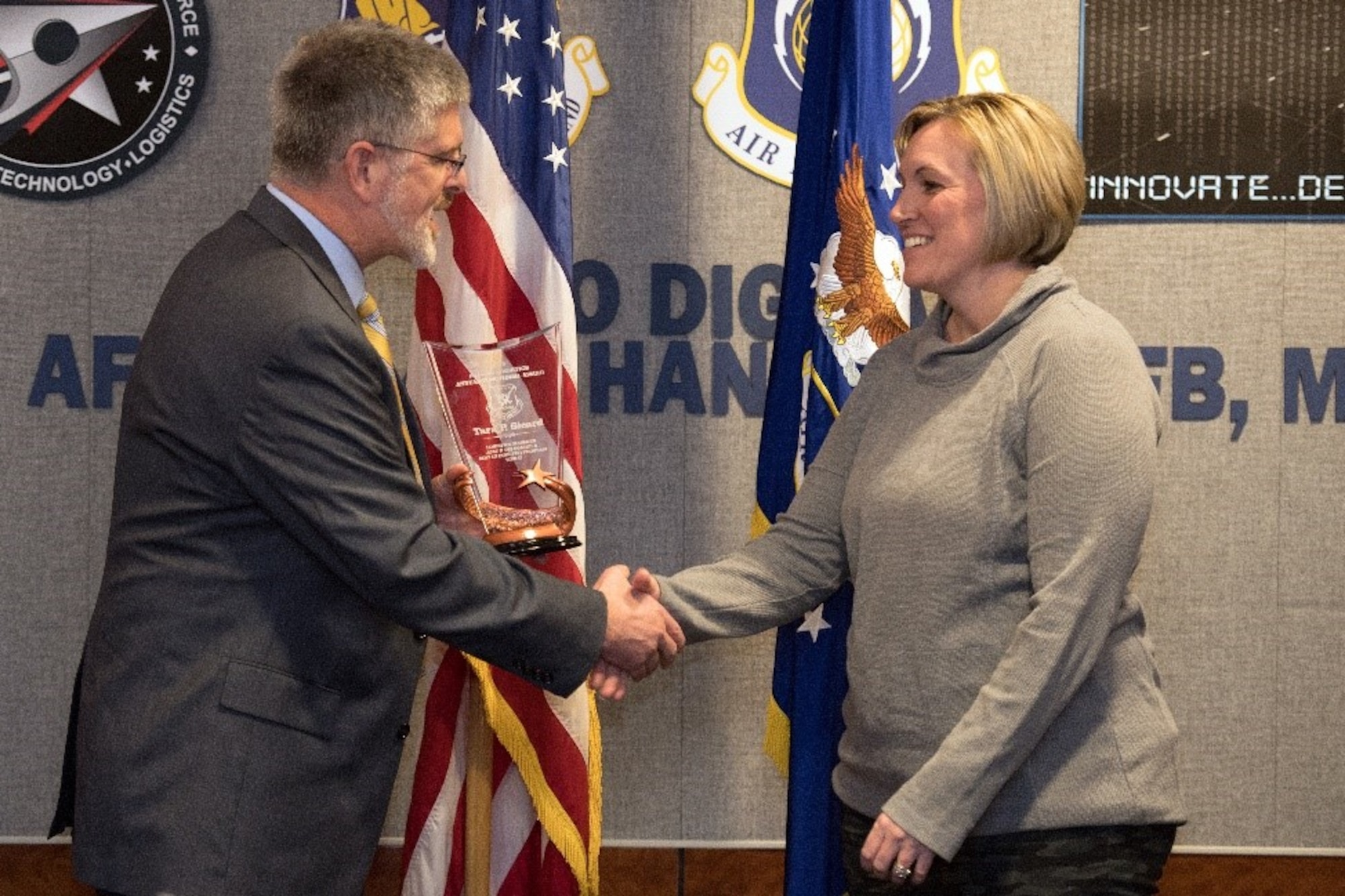 Scott Owens, deputy director of Command, Control, Communications, Intelligence and Networks Directorate, presents Tara Sicard, Base Infrastructure Branch chief, the Logistics Manager for ACAT I and II (non-flying) Tier II Award during an awards ceremony held at Wright-Patterson Air Force Base in Ohio and viewed by VTC at Hanscom Air Force Base, Mass., Feb.27. (U.S. Air Force photo by Jerry Saslav)