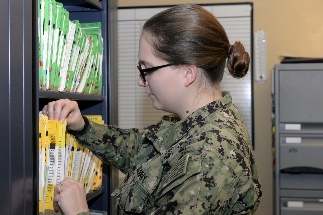 Lady in uniform looks through files.