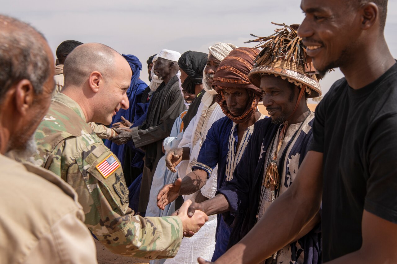 A soldier shakes hands with a line of men.