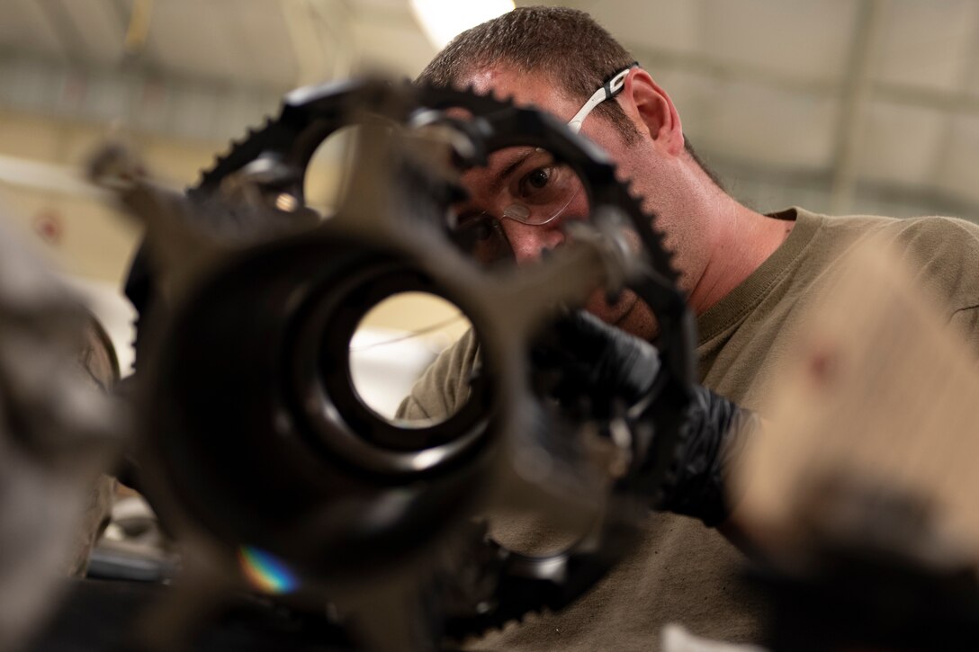A photo of an Airman safety-wiring a forward rotor to a mid rotor.
