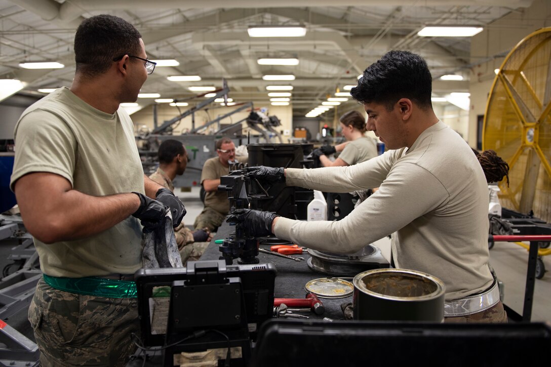 A photo of Airmen putting aircraft grease on a transfer unit.