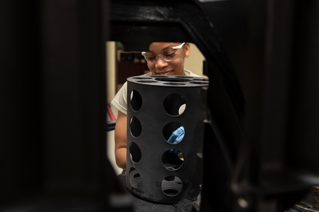 A photo of an Airman removing solid film lubricant from a muzzle clamp.