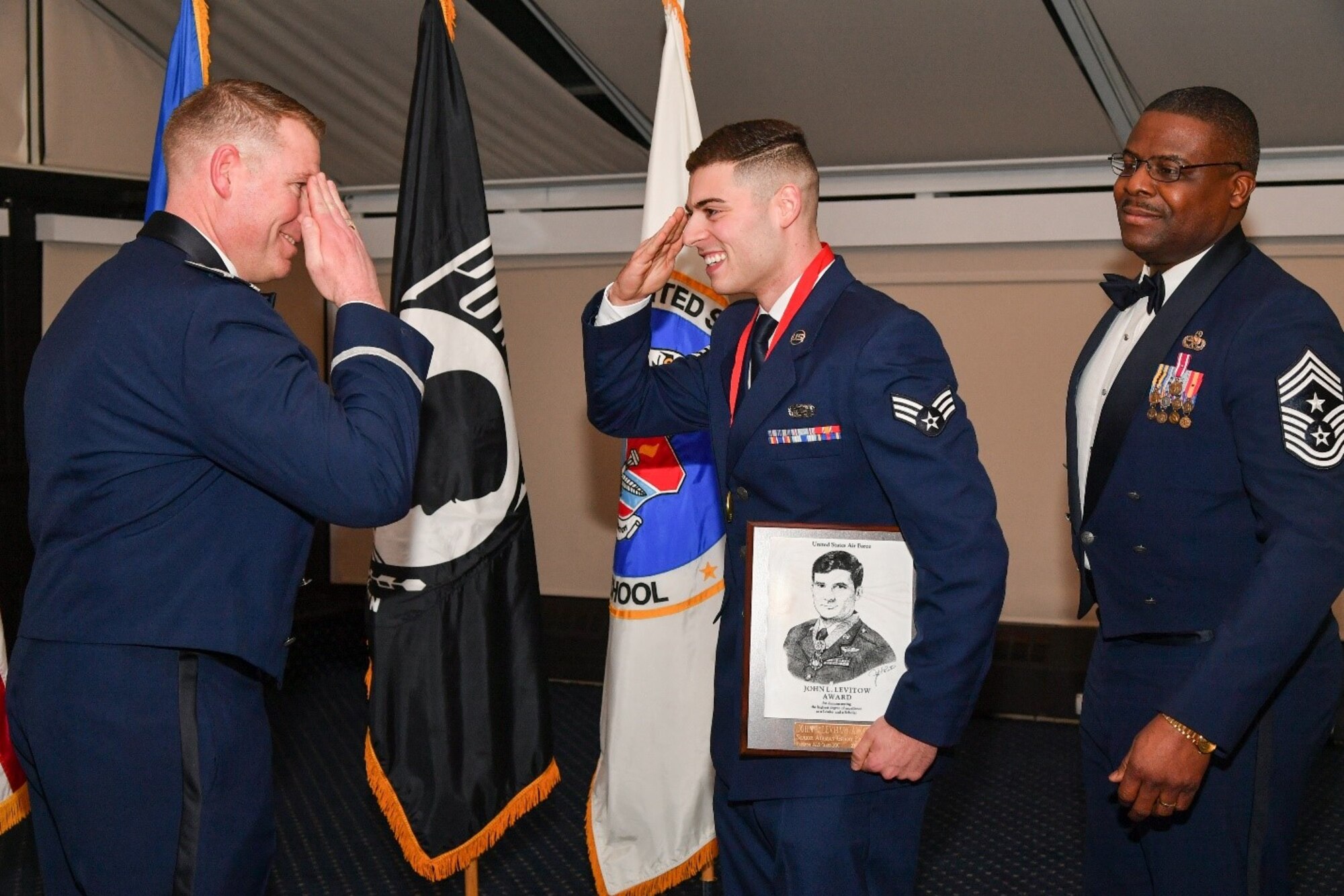 Col. Chad Ellsworth, left, 66th Air Base Group commander, returns a salute to Senior Airman Grant Killian, Hanscom Network Operations executive operation support administrator, during the Airman Leadership School graduation at Hanscom Air Force Base, Mass., Feb.27, while Chief Master Sgt. Henry Hayes, installation command chief, look on. Killian received the John Levitow award for demonstrating the highest degree of excellence as a leader and a scholar. (U.S. Air Force photo by Todd Maki)
