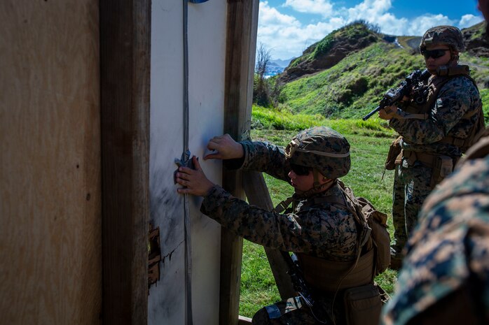 A U.S. Marine tapes detonation wire to a door during a demolition range, Marine Corps Base Hawaii, Feb. 26, 2020. The training event improved the Combat Assault Company and Combat Logistics Battalion 3 Marines' knowledge of explosives and breaching obstacles. (U.S. Marine Corps photo by Cpl. Matthew Kirk)