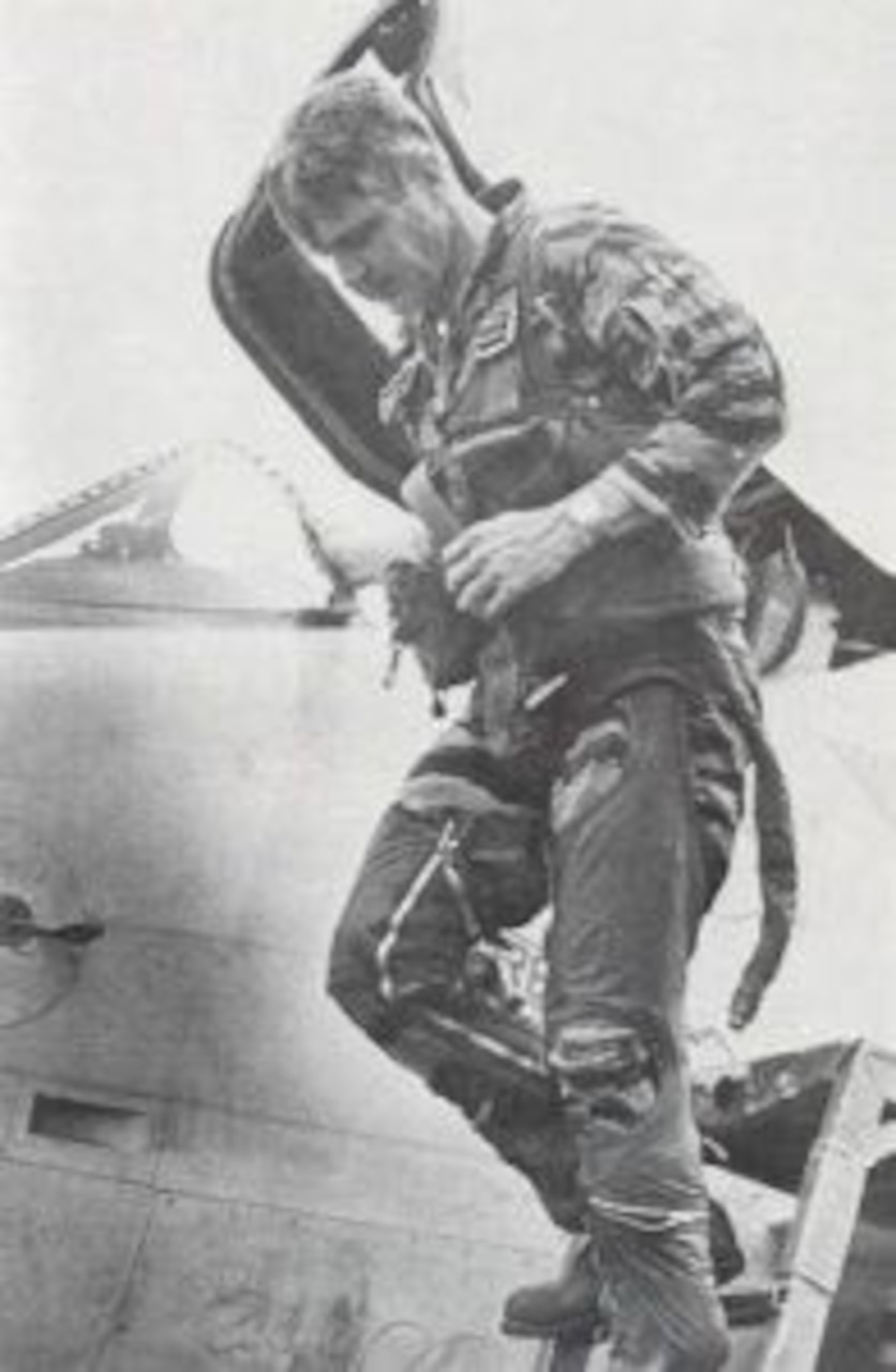 A pilot walks down the ladder off a jet’s cockpit.