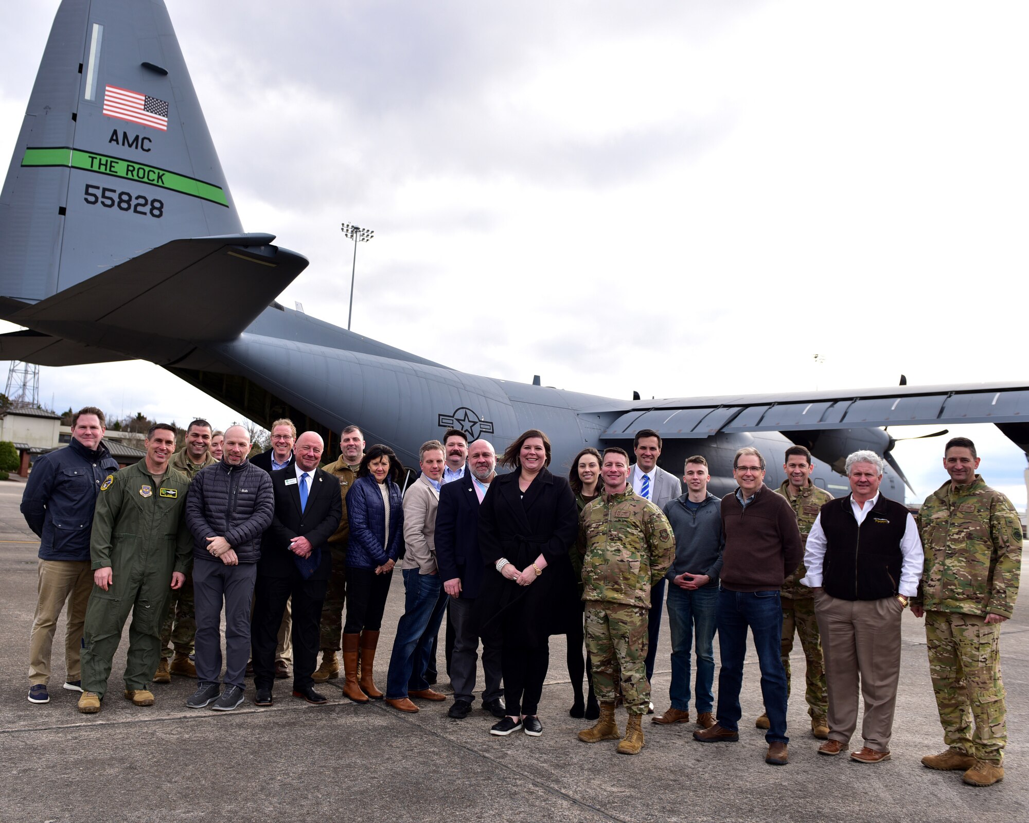 a group poses for a photo in front of a C-130J