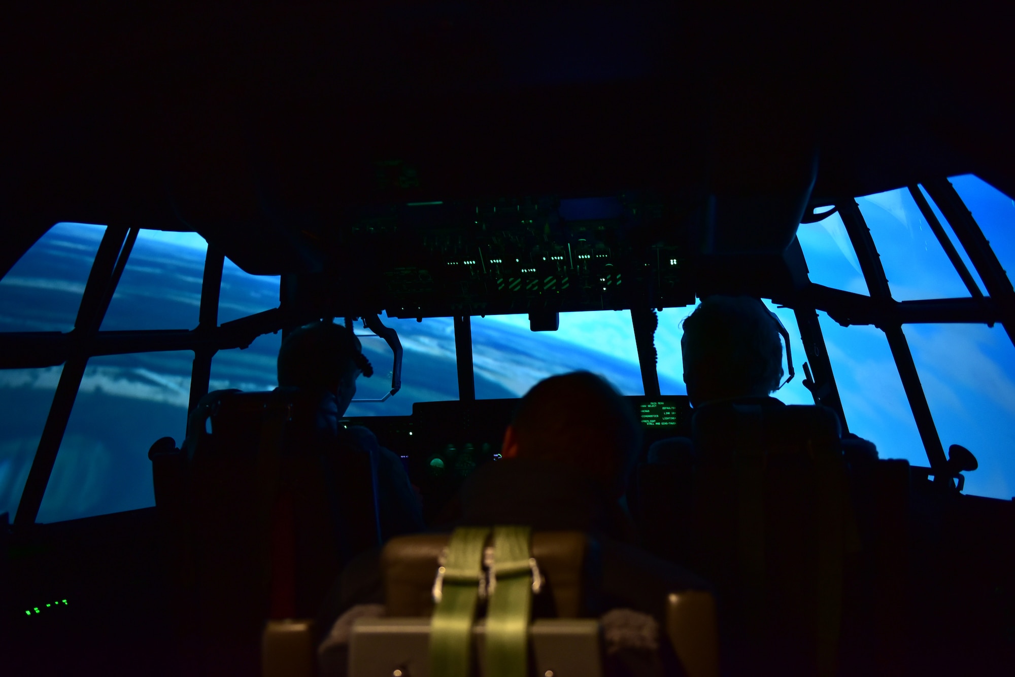 two people sit in a C-130J pilot simulator