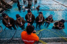An underwater egress training instructor with Marine Corps Base Hawaii teaches U.S. Marines with Headquarters Battalion, MCBH, how to use the Emergency Breathing System during Helicopter Underwater Egress Training, MCBH, Feb. 27, 2020. The training provides Marines with confidence to safely and efficiently exit a submerged aircraft in the event of a water landing. (U.S. Marine Corps photo by Cpl. Matthew Kirk)